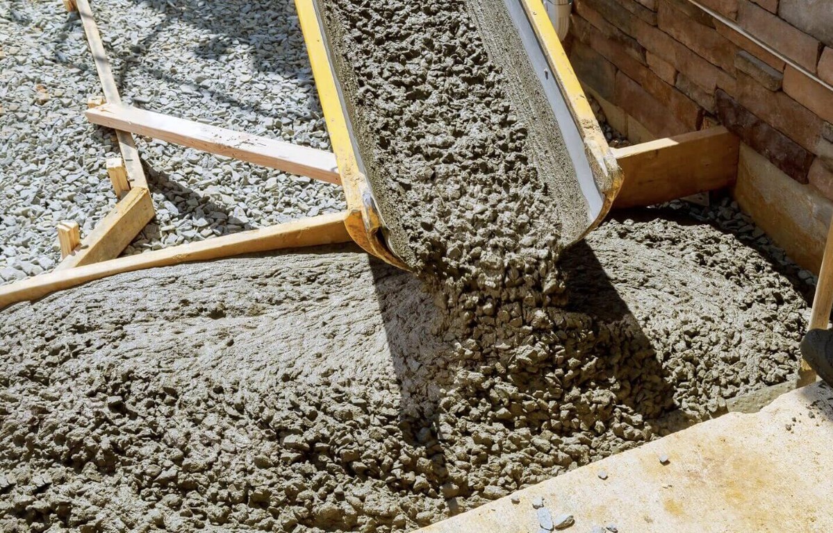 Fresh concrete being poured from a chute onto a prepared gravel base for a new patio in Little Rock, AR